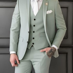 May include: A light green three-piece suit, comprising a blazer, waistcoat, and trousers. The blazer features a pocket square and a lapel pin. The waistcoat has black buttons. The text "GOODCHOICEBYSameer" is visible at the top.