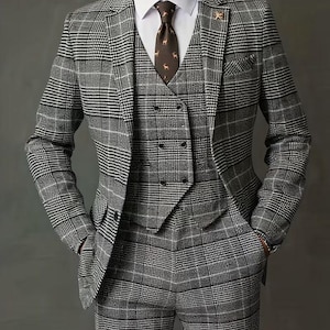 Puede incluir: Un traje de tres piezas a cuadros grises con camisa blanca y corbata estampada. El traje incluye una americana, un chaleco y un pantalón. La americana tiene un pañuelo de bolsillo y un prendedor. El texto "GOODCHOICEBYSameer" es visible en la parte superior.