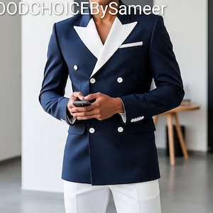 Może przedstawiać: Marynarka dwurzędowa w kolorze granatowym z białymi klapami i poszetką, połączona z białymi spodniami. Marynarka ma białe guziki i jest noszona z białą koszulą. Tekst "GOODCHOICEBySameer" znajduje się na górze.