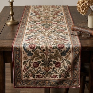 May include: A rectangular table runner featuring a woven pattern of scrolling acanthus leaves, blooming roses, and birds in shades of deep red, muted green, and blue on a cream background, finished with a dark red border along the edges.