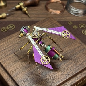 Könnte beinhalten: Steampunk-Insektenskulptur mit lila Flügeln, goldenen Zahnrädern und Messingakzenten. Das mechanische Insekt weist eine Kombination aus metallischen Farben und komplizierten Details auf.