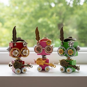 以下が含まれることがあります： 赤、ピンク、緑の3体のスチームパンク風ロボットフィギュア。各ロボットは歯車を眼とし、羽とミニチュアギターを備えています。ロボットは車輪付きで、様々な装飾要素があります。