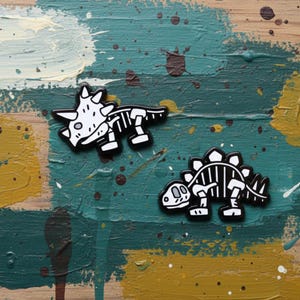 May include: Two black and white dinosaur skeleton pins. One is a Triceratops, the other a Stegosaurus. The pins are on a teal, yellow, and brown painted surface.