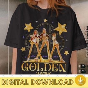 May include: Black t-shirt featuring a golden design with three stylized figures, stars, and the word "GOLDEN". The names "MIRA", "RUMI", and "ZOEY" are below the figures. The text "DIGITAL DOWNLOAD" is at the bottom.