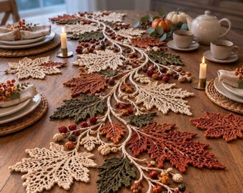 Puede incluir: Un camino de mesa de ganchillo largo con un patrón intrincado de hojas de otoño entrelazadas en color crema, naranja óxido y verde oliva, acentuado con pequeñas bayas y bellotas de ganchillo sobre una mesa de comedor de madera.