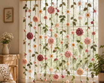 Puede incluir: Una cortina decorativa para ventana que presenta múltiples hilos verticales de enredaderas de ganchillo verde adornadas con varias flores rosas, blancas y crema. Los hilos florales cuelgan de una barra de madera horizontal en la ventana.