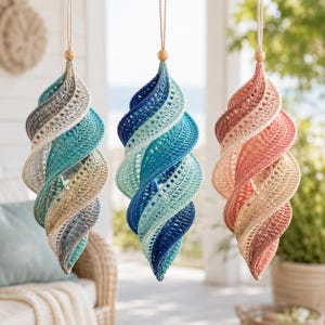 Puede incluir: Tres adornos en espiral colgantes hechos de hilo de ganchillo. Cada pieza presenta una forma alargada y retorcida con una cuenta de madera en la parte superior y un cordón. Los adornos muestran degradados de color turquesa, azul y coral.