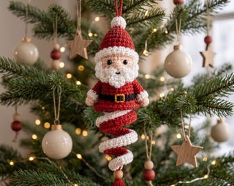Puede incluir: Un adorno de Papá Noel tejido a ganchillo con un gorro rojo de pompón blanco, barba blanca, chaqueta roja con cinturón negro y hebilla dorada, y una cola en espiral roja y blanca que termina en una cuenta de madera y una borla roja.