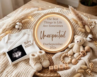 May include: A round wooden light-up sign with the text The Best Things in Life Are Sometimes Unexpected DueSeptember 202x, a white ribbed baby onesie with Baby Miller and an ultrasound image, cream knit booties, a small teddy bear, and wooden blocks.
