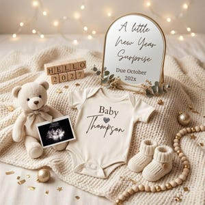 May include: A cream-colored baby bodysuit with the text Baby Thompson and a heart icon, a beige teddy bear holding an ultrasound photo, wooden blocks spelling HELLO 2027, a gold-framed mirror with the text A little New Year Surprise Due October 202x, and knit booties.