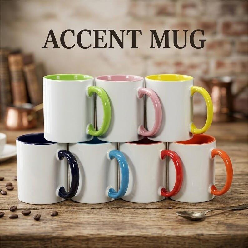 May include: A collection of seven white ceramic mugs arranged in two rows, each featuring a distinct colored interior and handle in lime green, pink, yellow, dark blue, light blue, red, and orange. The text ACCENT MUG is printed above them.