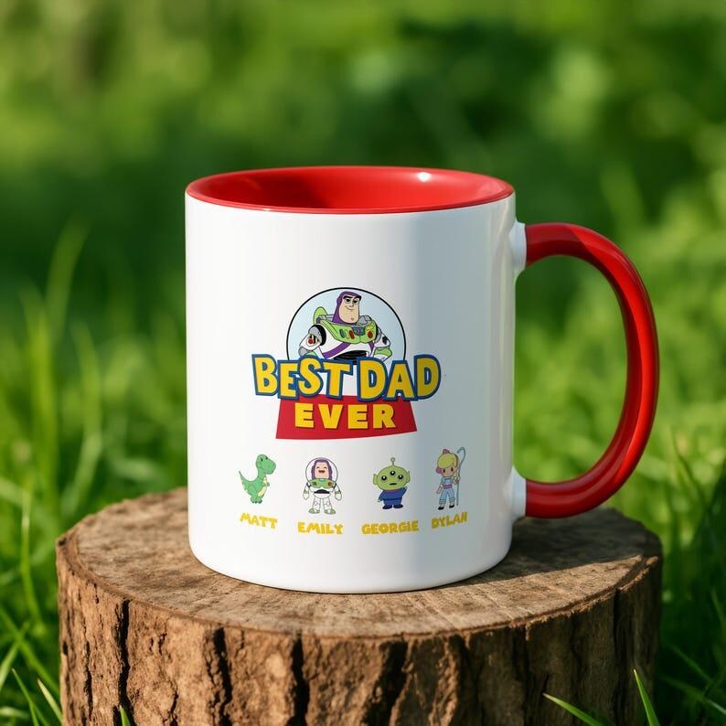 May include: A white ceramic mug with a red interior and handle. The front features a graphic of Buzz Lightyear above the text BEST DAD EVER. Below are four small cartoon characters with the names Matt, Emily, Georgie, and Dylan printed underneath.