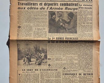May include: An old French newspaper with the headline "LES RUSSES A BERLIN". The page is filled with text and black and white photographs. The paper shows signs of age, with a faded, worn appearance.