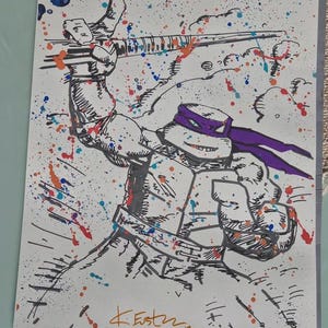 May include: Ink drawing of a Teenage Mutant Ninja Turtle, Donatello, with a purple mask, holding a bo staff. The artwork features a splatter effect with blue, orange, and red paint. Signed "K. Estz" with the year "18".