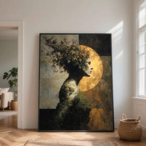 May include: A framed artwork depicts a profile of a figure composed of foliage and earth tones. The figure's head is adorned with leaves, set against a golden orb. The artwork is displayed in a room with natural light and a woven basket.