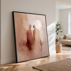 Könnte beinhalten: Abstrakter Kunstdruck mit zwei Figuren in gedämpften Rosa-, Beige- und Brauntönen. Das Kunstwerk ist mit einem schwarzen Rahmen versehen und lehnt an einer weißen Wand. Das Gemälde weckt ein Gefühl von Intimität und Kontemplation.