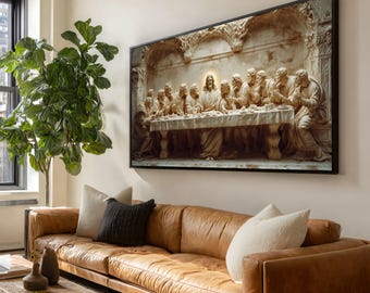 May include: A framed artwork depicting a relief sculpture of the Last Supper. The artwork is in a black frame and hangs above a brown leather sofa. The sculpture features figures seated around a table, with a central figure illuminated by a golden glow.