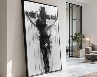 May include: Black and white framed artwork depicting a figure on a cross. The artwork features a dark, textured cross and a figure with a crown of thorns. Black paint drips down the white background, creating a dramatic effect. The frame is black.