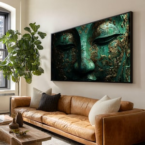 Può includere: Una stampa artistica incorniciata con un primo piano di un volto di Buddha. L'opera d'arte ha una combinazione di colori verde e oro con dettagli intricati. La stampa è esposta sopra un divano in pelle marrone.