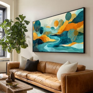Könnte beinhalten: Abstrakte Landschaftsmalerei in einem schwarzen Rahmen. Das Kunstwerk zeigt einen Fluss, der sich durch orangefarbene und blaugrüne Hügel schlängelt, mit stilisierten Bäumen und einem hellblauen Himmel. Das Gemälde wird über einem braunen Ledersofa ausgestellt.