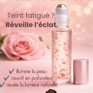 Peut inclure: Un flacon à bille en verre transparent rempli d'un liquide rose clair contenant des pétales de rose visibles. Le flacon possède une bille en argent et un bouchon rose clair. Le texte indique Rose de Damas, Teint fatigué ? Réveille l'éclat, et MoonRose.
