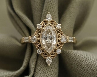 May include: A gold ring featuring a central marquise-cut diamond surrounded by smaller round and pear-shaped diamonds in a decorative filigree setting. The band includes baguette-cut diamonds on each side, with the text RoyaluniqueDesign visible.