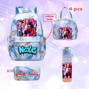 Może przedstawiać: Czteroczęściowy zestaw zawierający plecak, torbę na lunch, butelkę na wodę i piórnik. Elementy mają niebieski marmurowy wzór ze złotymi akcentami i grafiką trzech osób. Plecak ma imię "Nicolas" w niebieskim stylu graffiti.