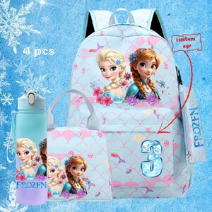 May include: A light blue backpack set featuring Elsa and Anna from Frozen. The set includes a backpack, lunch bag, water bottle, and pencil case. The backpack has a number 3 on the front and the words "custom age". The water bottle has the word "FROZEN".