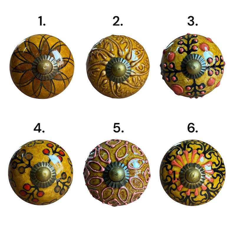 May include: A selection of six decorative cabinet knobs. Each knob has a unique design in shades of yellow, with red, pink, and black accents. The knobs have a brass-coloured base.