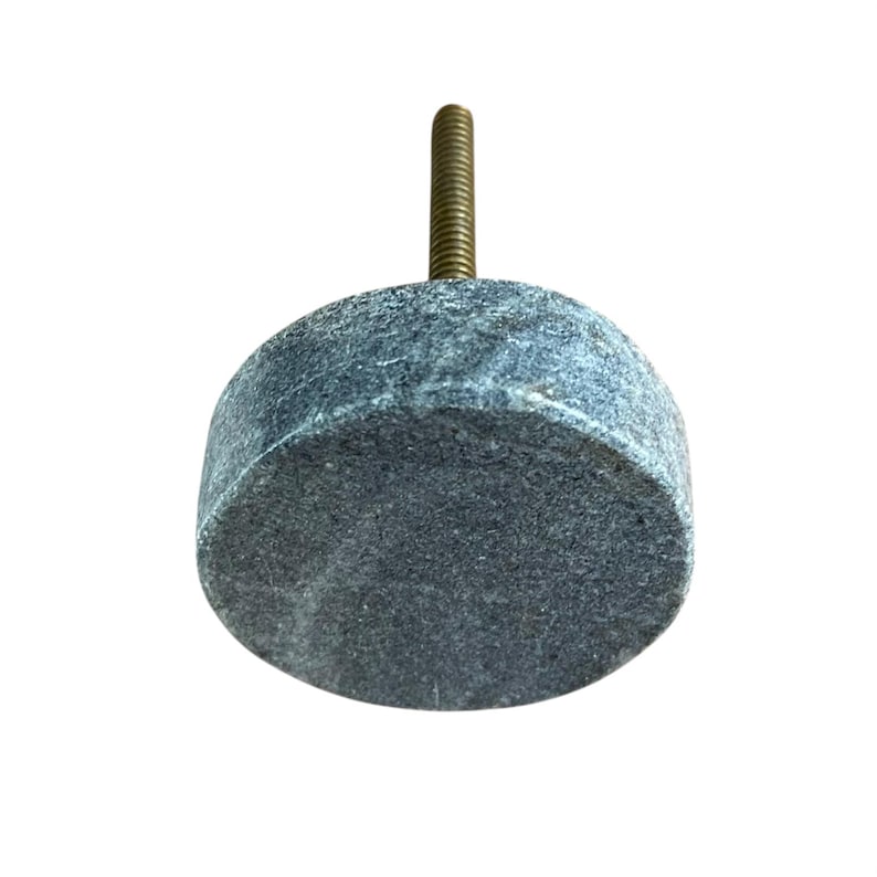 Pode incluir: Um puxador de arm&aacute;rio cil&iacute;ndrico cinza com um parafuso de lat&atilde;o roscado. O puxador &eacute; feito de um material manchado semelhante a pedra. O hardware &eacute; projetado para m&oacute;veis e decora&ccedil;&atilde;o de casa.