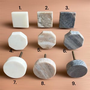 Pode incluir: Uma cole&ccedil;&atilde;o de nove puxadores de arm&aacute;rio de pedra em v&aacute;rias formas e cores. Os puxadores incluem designs quadrados, octogonais e arredondados, com cores que variam do branco e bege ao cinza. Cada puxador tem um parafuso de metal para instala&ccedil;&atilde;o.