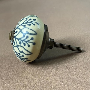 Puede incluir: Pomo de armario de cer&aacute;mica color crema con un dise&ntilde;o floral azul. El pomo tiene una base de metal y un tornillo roscado para la instalaci&oacute;n. El herraje tiene una est&eacute;tica vintage y es adecuado para cajones o armarios.