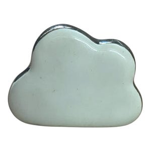 May include: A white cloud-shaped ornament with a silver edge. The cloud has a smooth, shiny surface and a rounded form. The object is probably ceramic or porcelain and could be used as a decorative accent in a home.