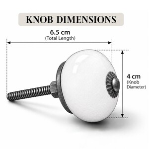 May include: A white ceramic cabinet knob with a dark metallic base and a decorative center cap. The text KNOB DIMENSIONS is displayed above. The total length is 6.5 cm and the knob diameter is 4 cm as indicated by the measurement lines.