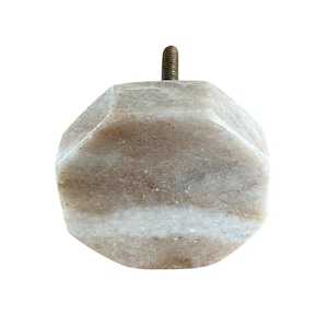 Pode incluir: Um puxador decorativo para arm&aacute;rio com um design geom&eacute;trico facetado. O puxador &eacute; feito de uma pedra bege clara e branca, com um parafuso de lat&atilde;o para fixa&ccedil;&atilde;o. A pedra tem uma apar&ecirc;ncia natural marmorizada.