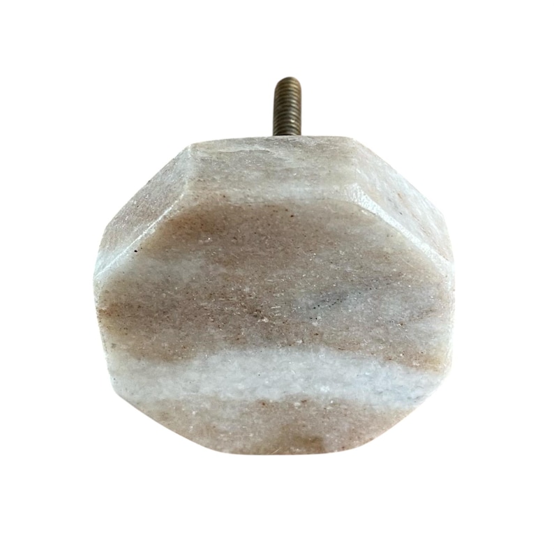 Pode incluir: Um puxador decorativo para arm&aacute;rio com um design geom&eacute;trico facetado. O puxador &eacute; feito de uma pedra bege clara e branca, com um parafuso de lat&atilde;o para fixa&ccedil;&atilde;o. A pedra tem uma apar&ecirc;ncia natural marmorizada.