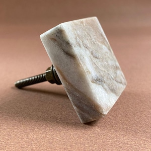 Pode incluir: Puxador de arm&aacute;rio quadrado em m&aacute;rmore com parafuso de lat&atilde;o. O puxador &eacute; branco com veios castanhos. A ferragem &eacute; de cor lat&atilde;o. Este puxador decorativo &eacute; adequado para gavetas e arm&aacute;rios.