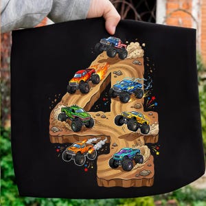 May include: Black graphic featuring the number 4 with monster trucks driving on a dirt track. The trucks are in various colors, including red, blue, green, and yellow, with flames and lightning bolts. The design is on a black background.