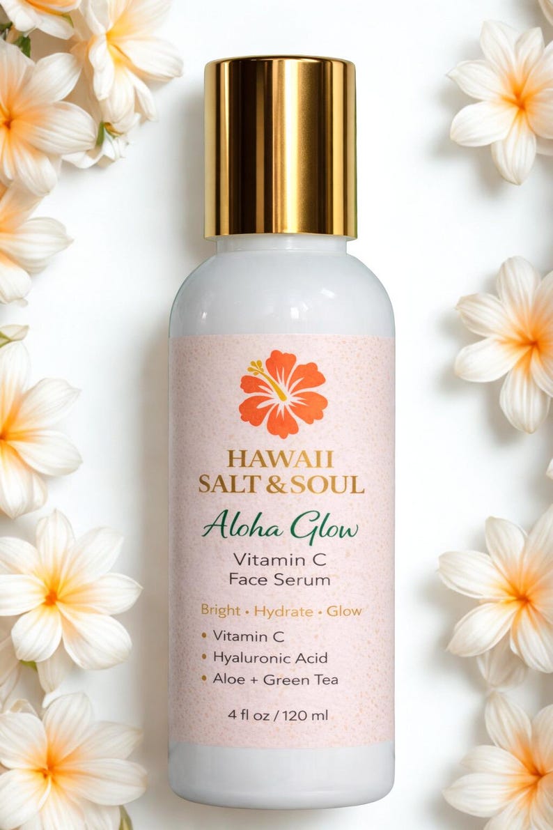 May include: A white bottle of Hawaii Salt & Soul Aloha Glow Vitamin C Face Serum with a gold cap. The label features a hibiscus flower and the text "Aloha Glow". The bottle is surrounded by white and yellow flowers.