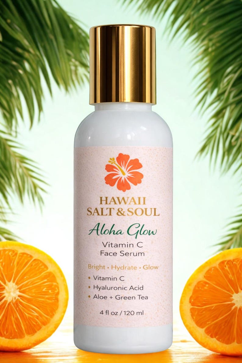 May include: A white bottle of Hawaii Salt & Soul Aloha Glow Vitamin C Face Serum with a gold cap. The label features a hibiscus flower and the text "Aloha Glow". The bottle is 4 fl oz / 120 ml. Two orange halves flank the bottle.