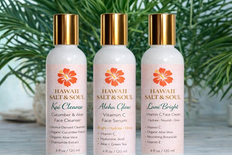 May include: Three white bottles of Hawaii Salt & Soul skincare products with gold caps and pink labels. Each label features an orange hibiscus flower and product name: Kai Cleanse, Aloha Glow, and Lani Bright. Each bottle contains 4 fl oz / 120 ml.