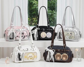 May include: Five shoulder bags in various colors: pink, black, white, silver, and navy blue. Each bag has a rectangular shape with a top handle and a decorative charm. The bags feature clear pockets with cartoon character designs.