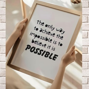 May include: A framed print with a light wood frame. The white paper features black text that reads: "the only way to achieve the impossible is to believe it is POSSIBLE."