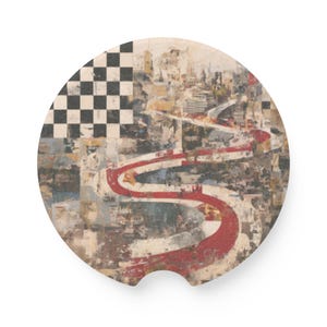 May include: Round car coaster with an abstract design. The coaster features a checkered flag pattern in black and white, a red and white winding road, and a cityscape background. The coaster is made of a durable material.