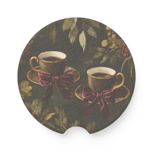 May include: Round car coaster featuring two teacups filled with coffee, each on a saucer and adorned with a burgundy bow. The background is a dark green with a botanical design of leaves and berries.