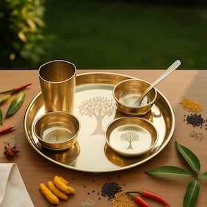Könnte beinhalten: Ein goldenes Messing-Geschirrset mit einem großen runden Tablett, einem hohen Glas, drei kleinen Schalen und einem Löffel. Das Tablett und die Schalen sind mit einem Baumdesign verziert. Das Set wird auf einer Holzoberfläche präsentiert.