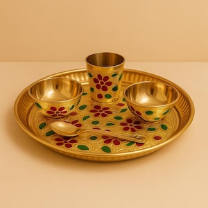 Könnte beinhalten: Ein goldenes Messing-Geschirrset mit einem runden Tablett, zwei kleinen Schalen, einem Becher und einem Löffel. Das Set ist mit roten und grünen Blumenmustern verziert. Das Tablett hat einen Durchmesser von ca. 25 cm.