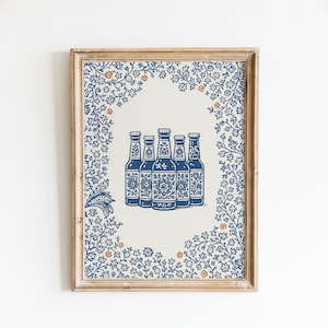 Może przedstawiać: Oprawiony wydruk artystyczny przedstawiający pięć niebiesko-białych butelek piwa z kwiatowymi wzorami. Butelki znajdują się na kremowym tle, otoczone niebieską kwiatową obwódką z pomarańczowymi akcentami. Rama jest w jasnym kolorze drewna.