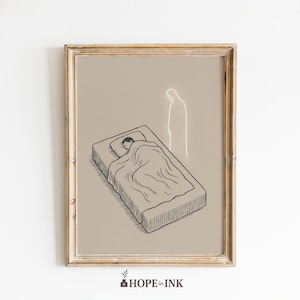 May include: Framed art print featuring a black and white illustration of a person sleeping in a bed, with a glowing outline of a figure standing nearby. The artwork is set against a neutral background and framed in a gold-toned wooden frame. The text "HOPE in INK" is at the bottom.