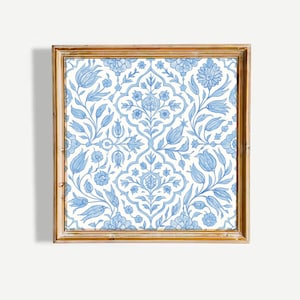May include: Square framed art print with a light blue floral design on a white backdrop. The pattern showcases stylized flowers, leaves, and vines. The frame is a warm, light brown, providing a classic aesthetic to the artwork.